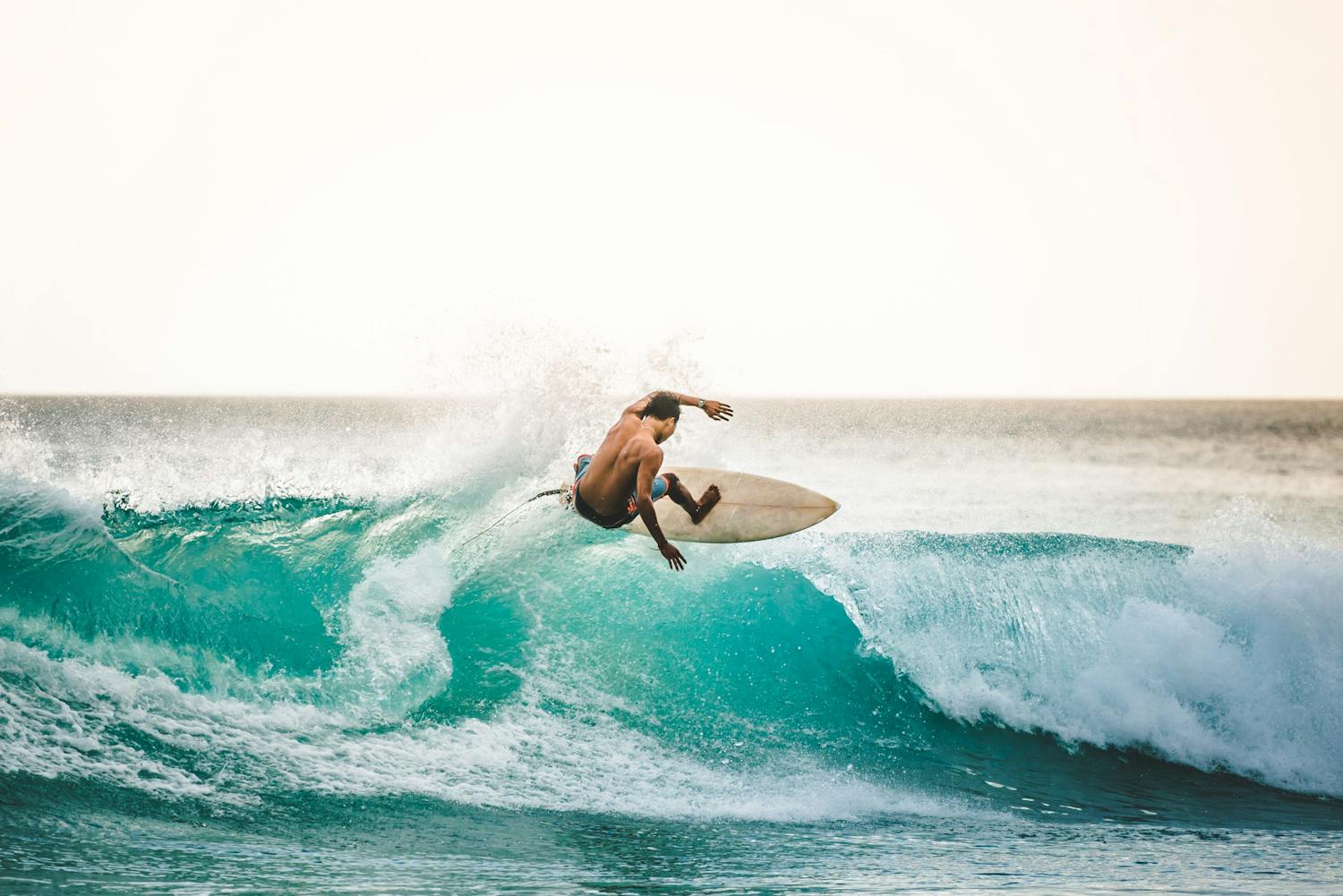 shutterstock 1591974517 B66GYoAHPGe7 Mand surfer ved stranden.